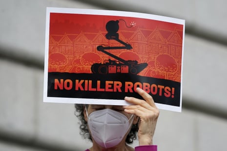 A woman holds up a sign while taking part in a protest about the use of robots by the SFPD.