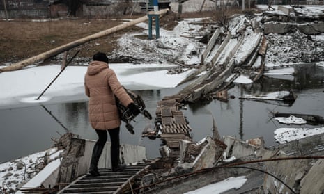 A woman walks on a destroyed bridge in Bakhmut