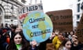 Young people at a protest holding signs including 'climate not capitalists'