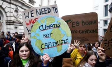 Young people at a protest holding signs including 'climate not capitalists'