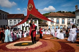 People walk over a sawdust carpet under a big red banner