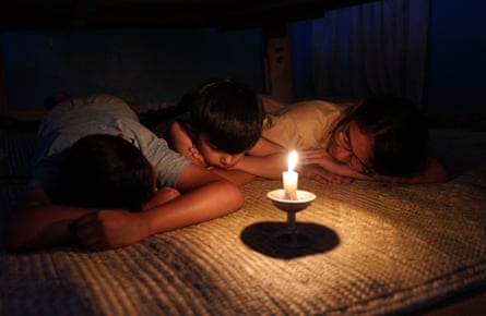 Three children lying on the floor with a candle