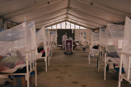 Patients lie under mosquito nets in a tent