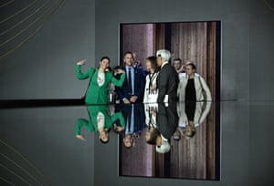 A group of people smiling, reflected in the shiny table they are standing next to