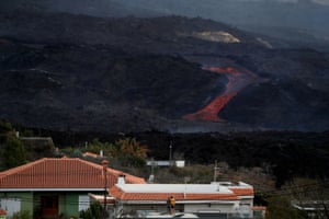 People look at lava spewed from the Cumbre Vieja volcano from a house