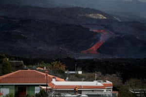People look astatine lava spewed from the Cumbre Vieja volcano from a house