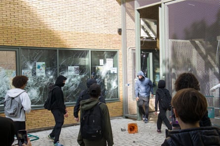 Young men in masks attack windows of a school