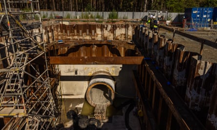 Two people look down at the launch chamber of a gas pipeline