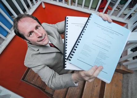 man in a suit holding up two bound documents