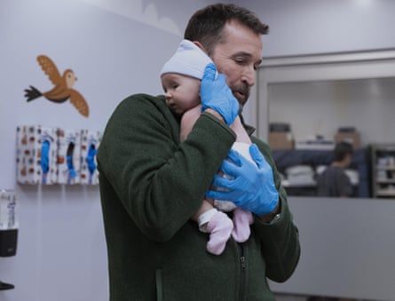 A doctor holding a baby on his shoulder