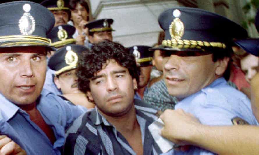 Diego Maradona escorted by police as he leaves a courthouse after answering charges he shot and injured journalists, March 1994.
