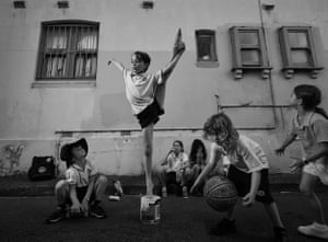 A group of young children playing in a street while one practices their ballet in the middle.