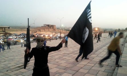 A fighter of the Islamic State of Iraq and the Levant (ISIL) holds an ISIL flag and a weapon on a street in the city of Mosul, Iraq on 23 June 2014.