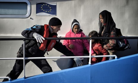 A coastguard helps children disembark from a Frontex ship