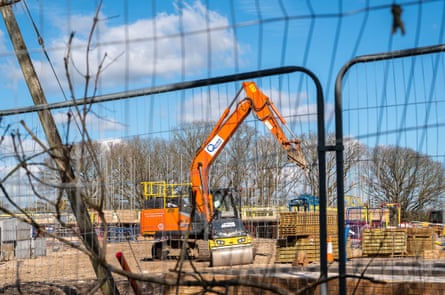 A housing development and crane seen through a fence.