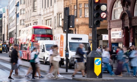 pedestrians cross road with cars and buses queuing on Oxford Street, central London.