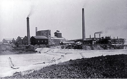 A black and white image of buildings and towers emitting smoke
