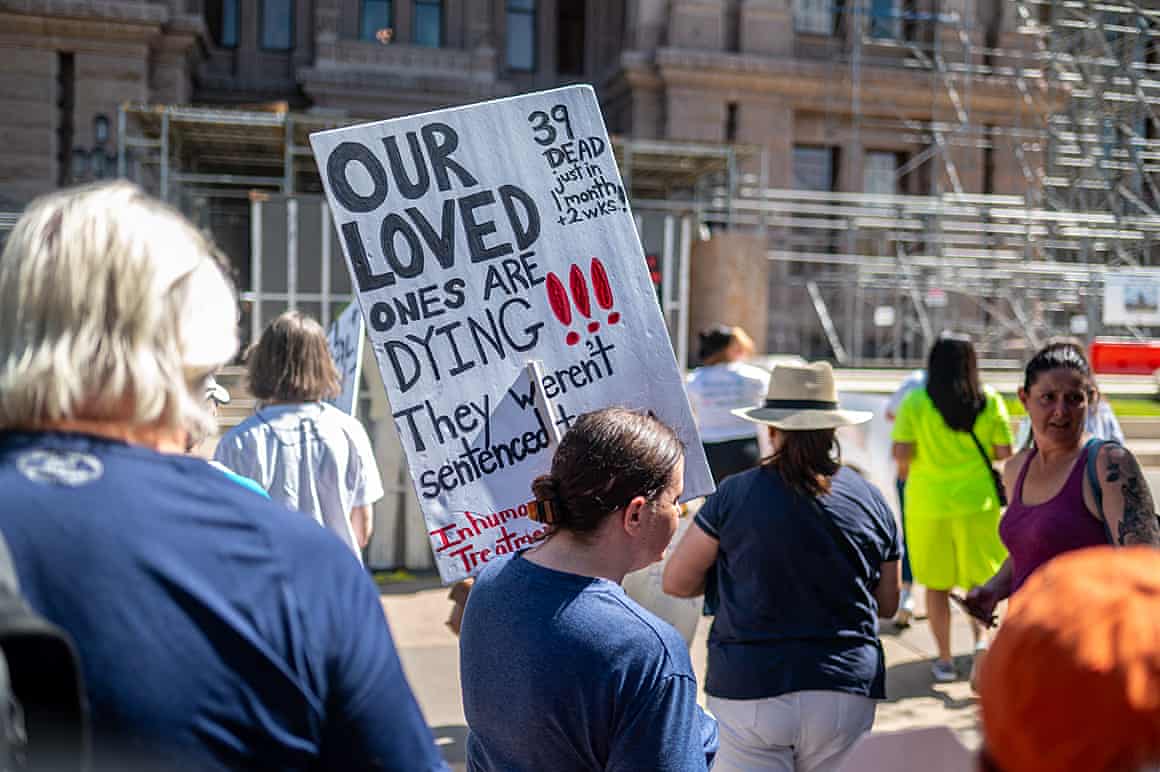 Demonstrators walk toward the Texas State Capitol building in Austin, Texas, with one holding a sign saying “our loved ones are dying”.