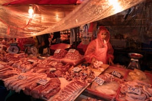 A stallholder selling meat products wearing a plastic poncho
