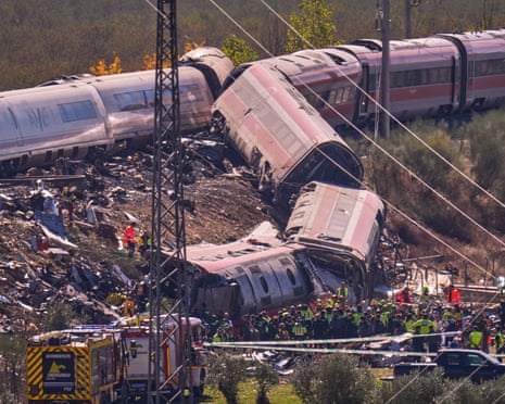 Derailed, crumpled train carriages lie stacked at an angle as emergency crews work in Urda, Spain
