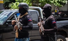 Masked Haitian police officers carry rifles on patrol