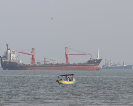 A small fishing boat floats near a large cargo ship off Bandar Abbas, Iran