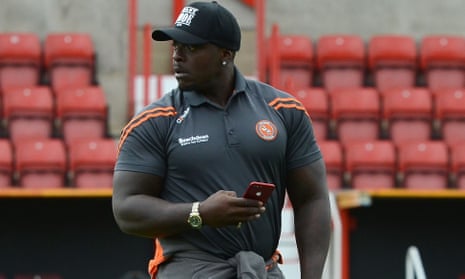 Wycombe’s Adebayo Akinfenwa, phone in hand, inspects the pitch before last month’s match at Swindon.