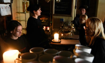 People sit in a cafe without electricity in the western Ukrainian city of Lviv, after Russian missiles targeted energy infrastructure on 11 October 2022.