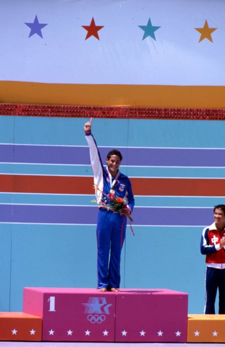 Louganis in US team tracksuit raises his hand in the air in celebration at the men’s 10-metre platform medal ceremony at the 1984 Los Angeles Olympics.