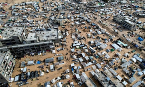 An aerial view of many tents spread across sandy earth around a mosque