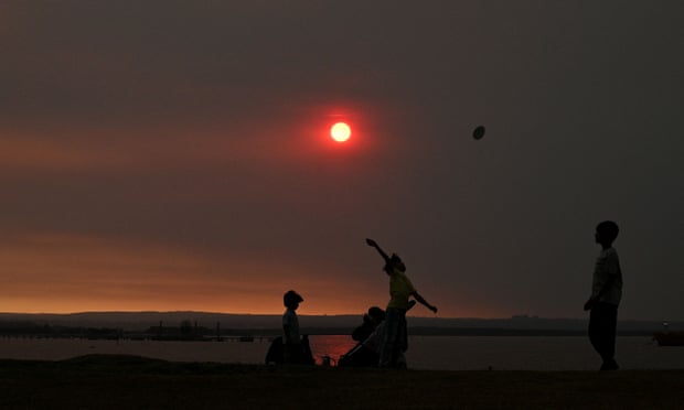A family at a beach in Sydney as smoke haze hangs over the city