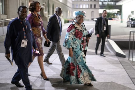 A group of people leaving an office, with the WTO chief wearing traditional Nigerian prints and a headdress