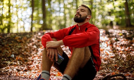 Retrato de jovem relaxado com fones de ouvido bluetooth na floresta