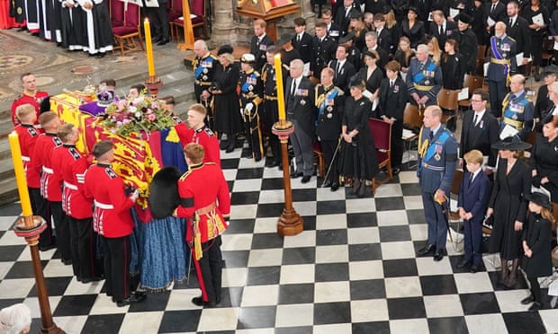 Prince Harry stands behind King Charles while Prince William stands in the front row.