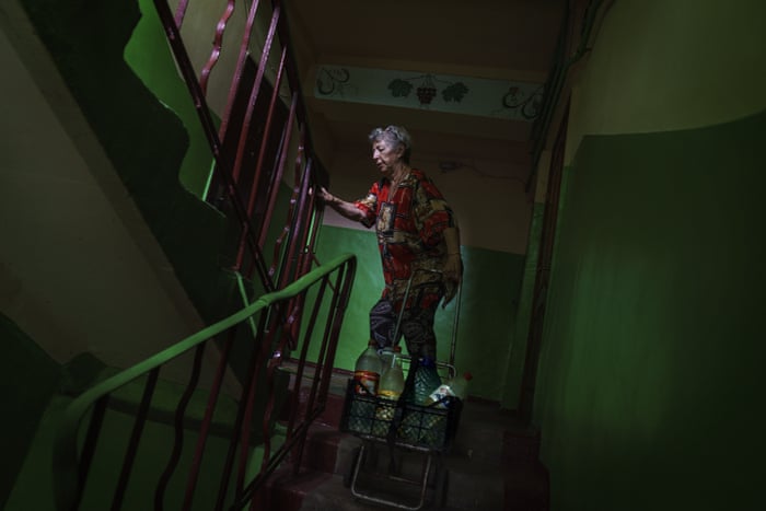 Lyubov Mahlii, 76, pulls a crate of water bottles up the stairs to her fifth floor apartment after filling them up at a nearby park in Sloviansk. A lack of running water in the city means that residents must fill bottles by hand at public pumps.