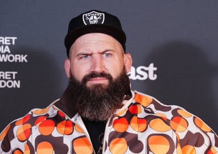 Joe Marler in black cap and orange and brown shirt.