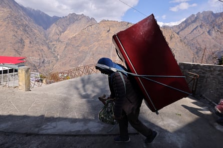 A labourer carries a fridge belonging to Ganesh Devi Rawat, 68, who vacated her house after cracks developed.