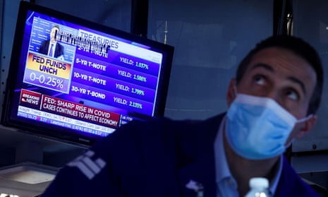 A screen displays the Fed rate announcement as a specialist trader works at his post on the floor of the New York Stock Exchange today.