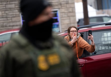 person wearing orange blows whistle while in a red car