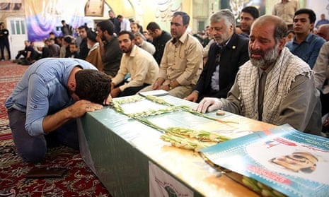Mourners gather around the bodies of Iranians killed in Syria, during their funeral in Mashad, Iran