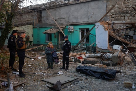 A woman stands next to the body of her neighbour, found under debris of a residential house destroyed by a Russian missile attack in Mykolaiv.