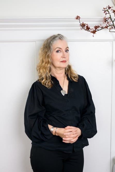 A woman in black leaning against a white panelled wall with a spring of cherry blossom to her right