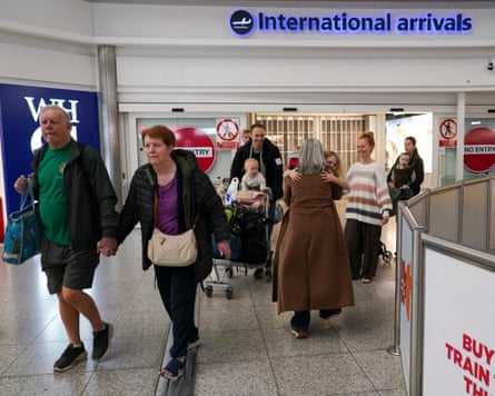 People at an airport walk through a door marked international arrivals