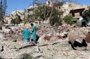 Syrian people inspect the pit around the Sahra hospital after a barrel bomb strike by Syrian regime forces