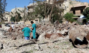 People inspect the pit around the Sahra hospital after a barrel bomb strike on 1 October.