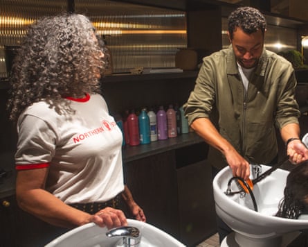 A man washes a woman’s hair while another woman looks on