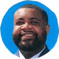 man in suit smiling outside with blue background