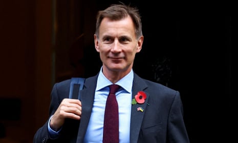 The chancellor, Jeremy Hunt, walks out of the doorway to No 10 Downing Street while carrying a rucksack and wearing a poppy