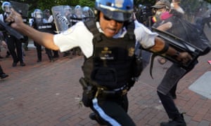 An officer swings a baton as demonstrators clash with police near the White House in Washington on 30 May.
