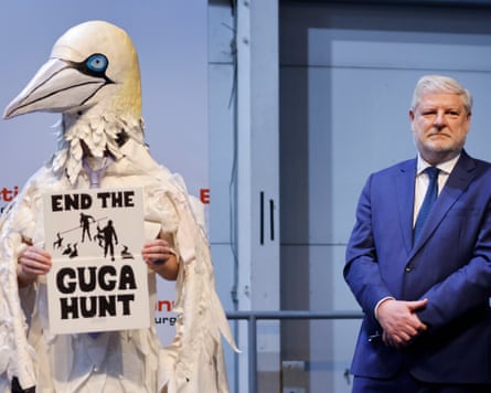 A candidate in a gannet costume holds a sign reading 'end the guga hunt'